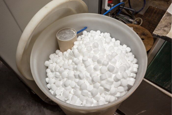 Container of new salt pellets for extending water softener lifespan