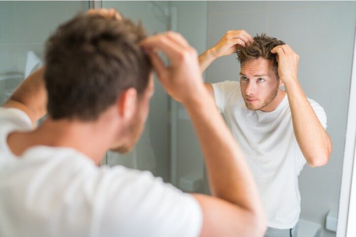 Man examining scalp and hair for dryness or residue