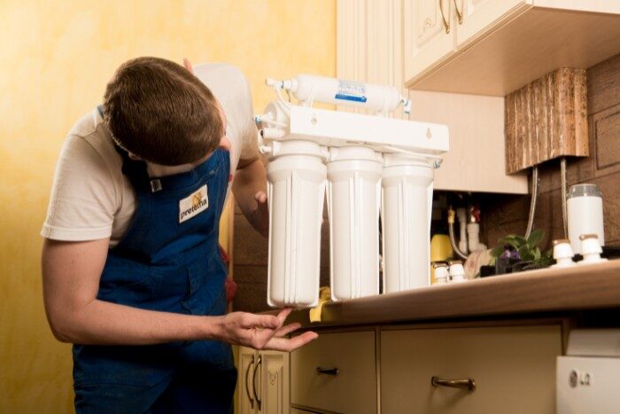 Technician doing routine maintenance to a water filtration system to improve home value