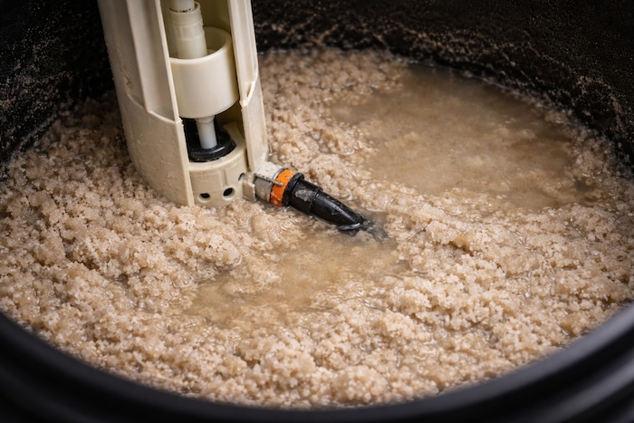 Mushing sludge buildup at the bottom of a water softener brine tank