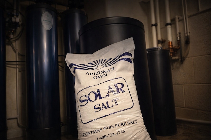Solar salt bag leaning beside brine tank and water softener system