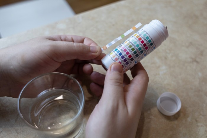 Comparing a home water test strip to the color chart